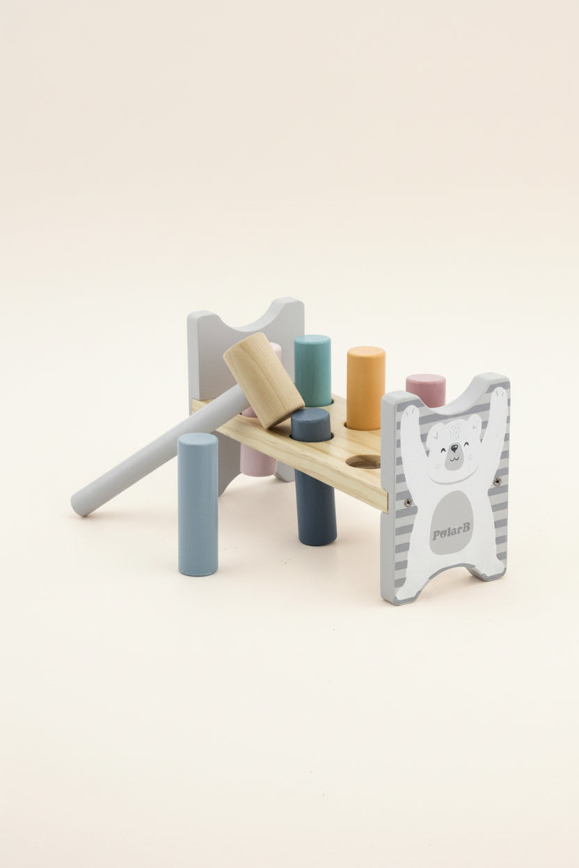 A wooden toy block hammer set by PolarB, featuring a light natural wood mallet, colorful wooden pegs in blue, teal, orange, pink, and navy, and a white bear-themed guard with gray stripes.