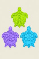 Three colorful turtle-shaped stepping stones textured  in purple, blue, and lime green arranged on a light wood surface.