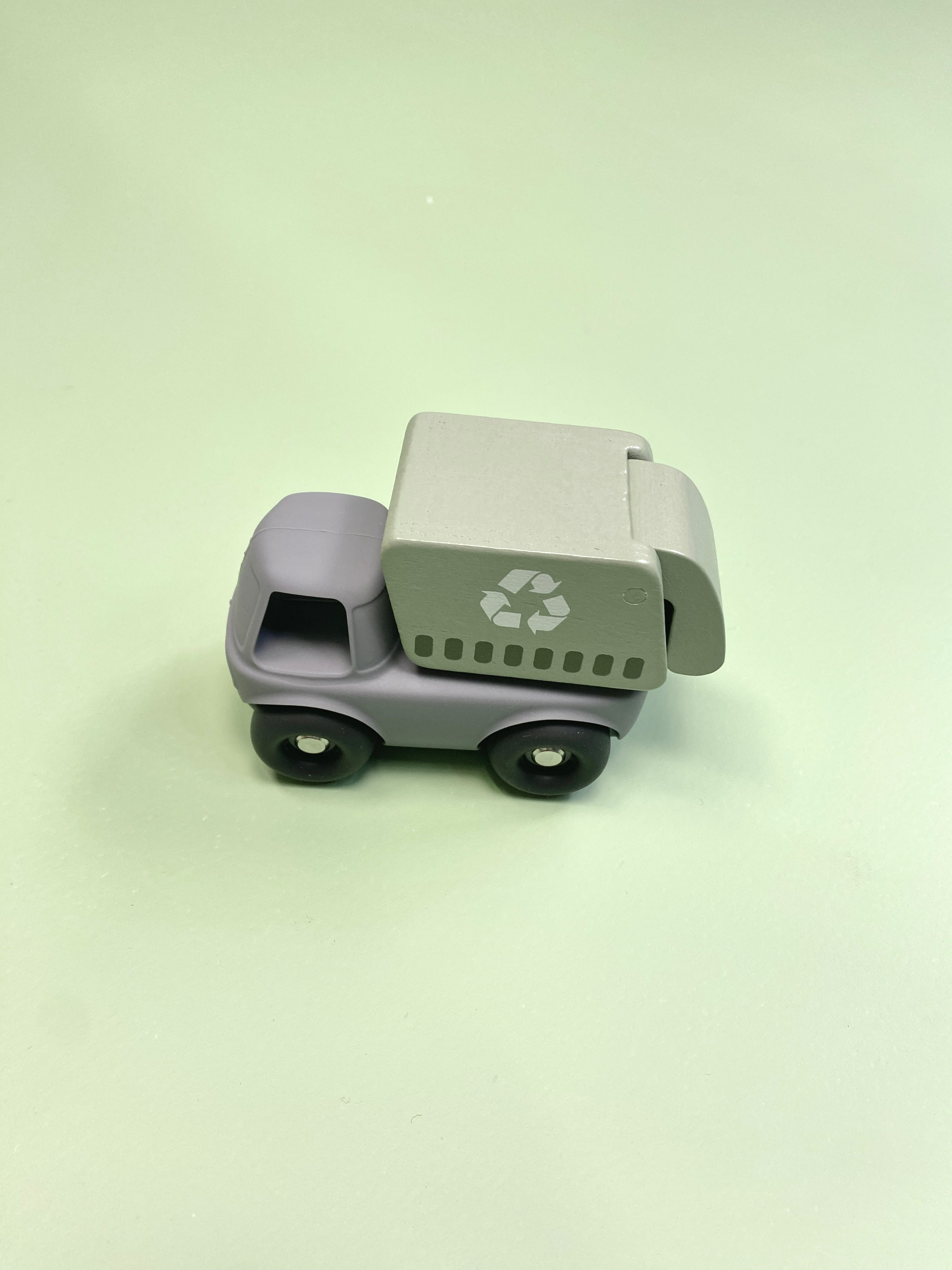 Toy garbage truck with recycling symbol on a light green background