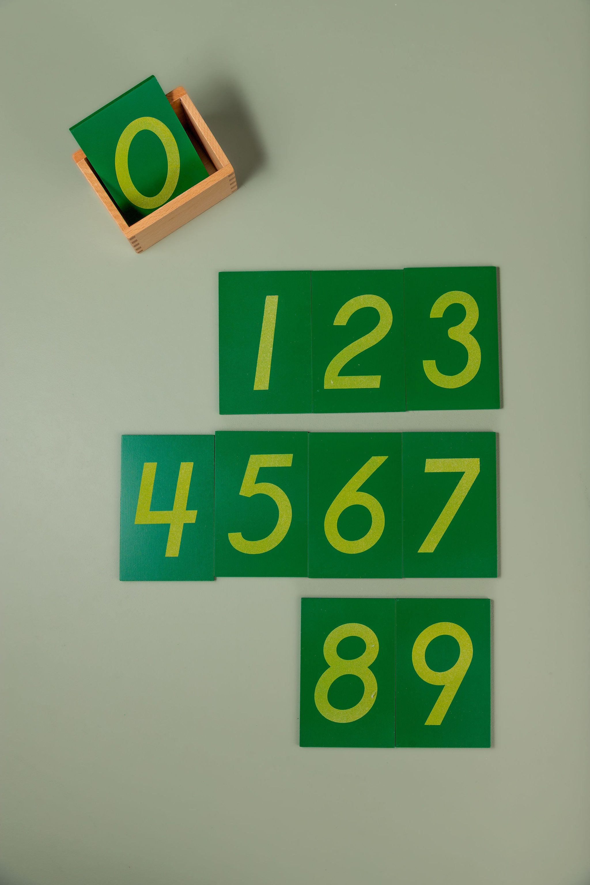The full set of ten numeral boards stacked inside the wooden storage box to show the compact, tidy set size.