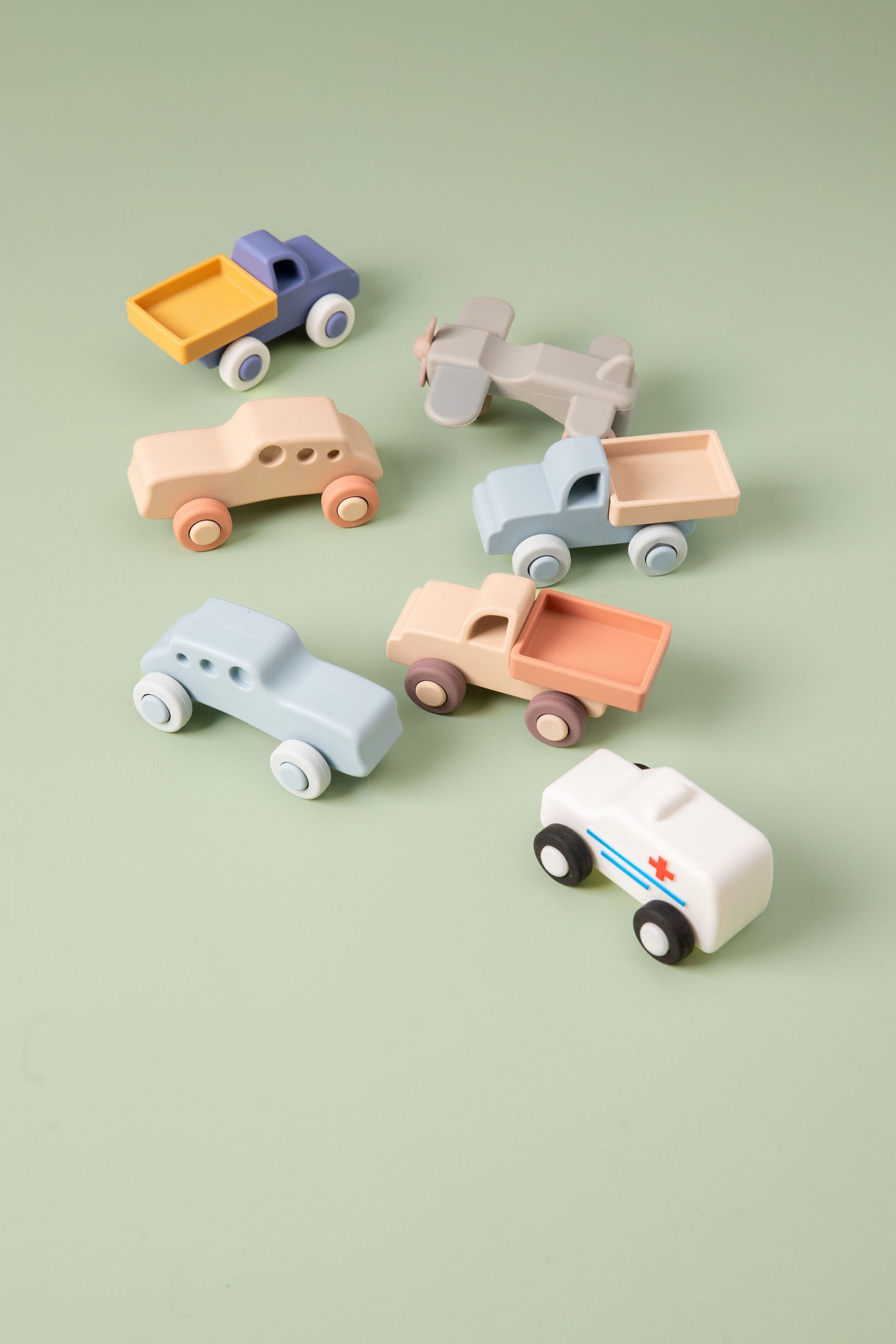 Set of colorful silicone toy cars on a light green background