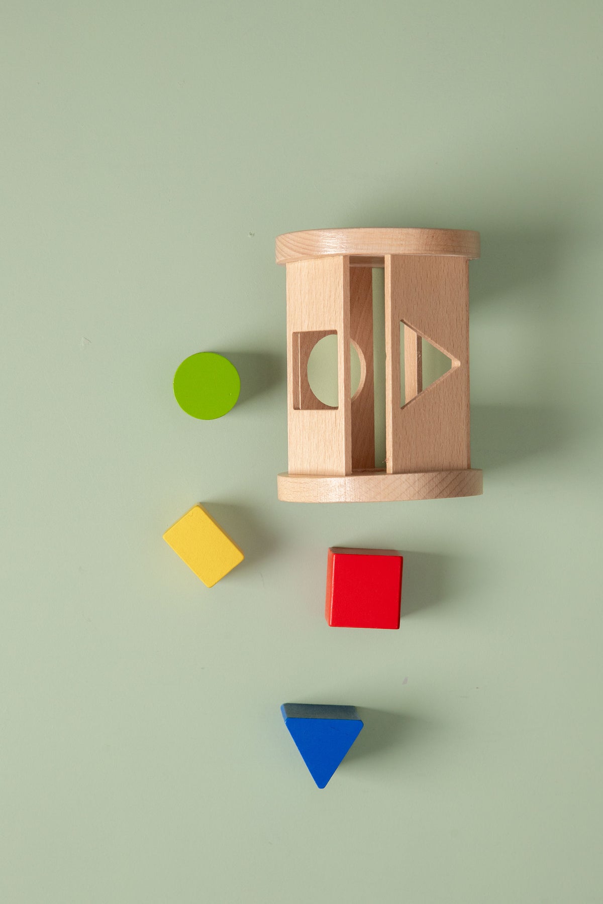 Wooden shape sorter with colorful blocks on a light green background