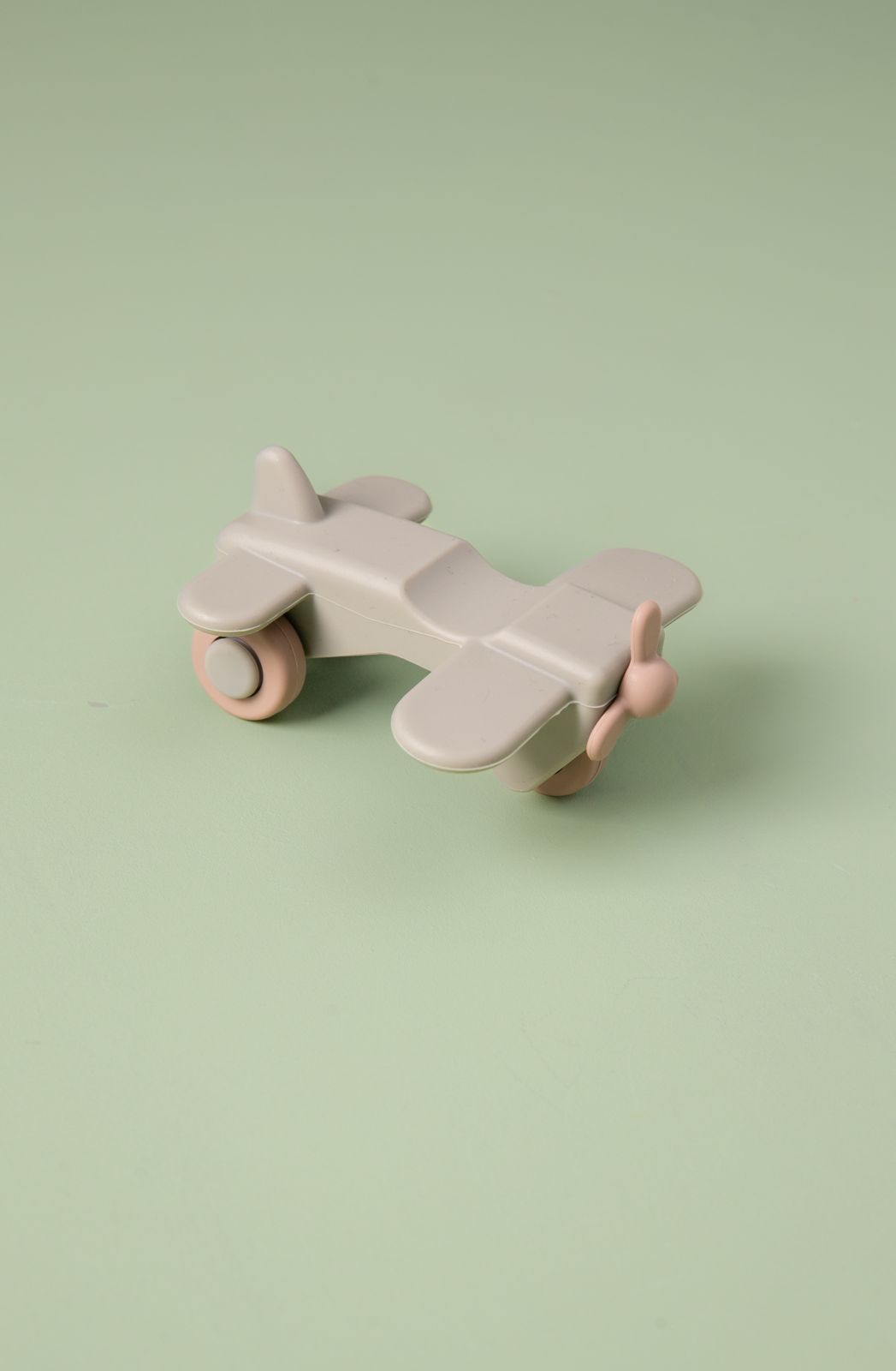 Toy airplane on wheels with pink accents on a light green background