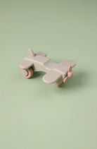 Toy airplane on wheels with pink accents on a light green background