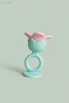 A baby teether toy with a light blue suction base and ring handle, featuring a pink flower-shaped top, placed on a light wooden surface.
