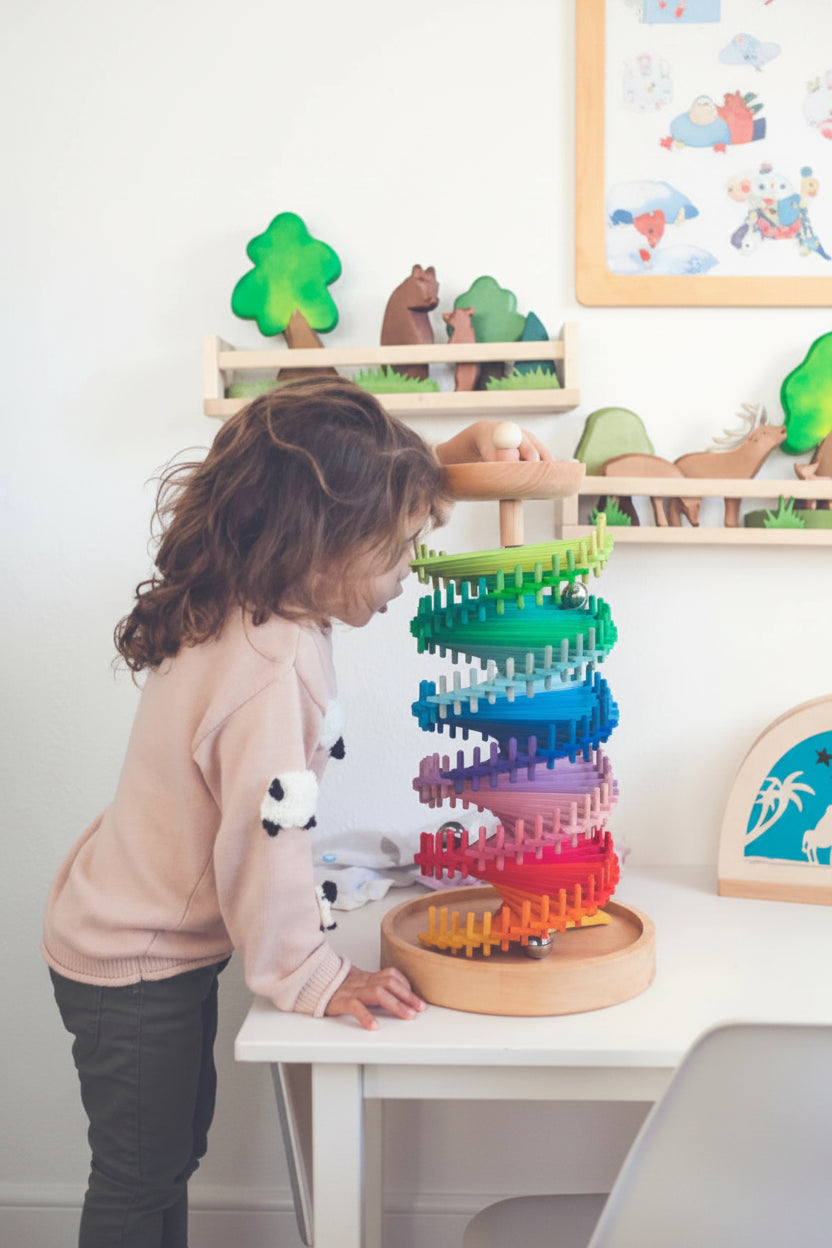 Child dropping a wooden marble into the top of the rainbow marble tower